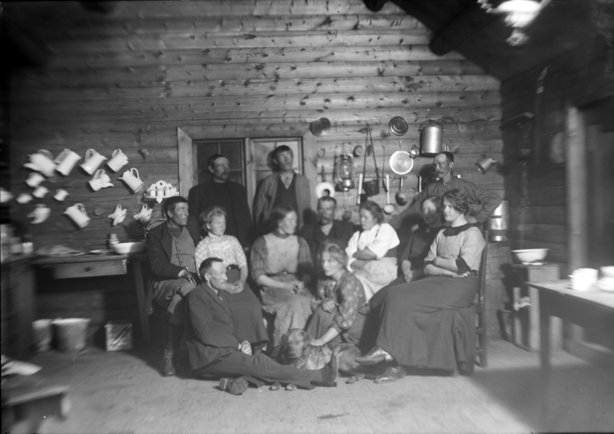 Sjodalen, Bessheim, gruppe kvinner, menn og en hund klar for fotografering på kjøkkenet. Kjøkkenredskap og mugger hengt opp på veggen