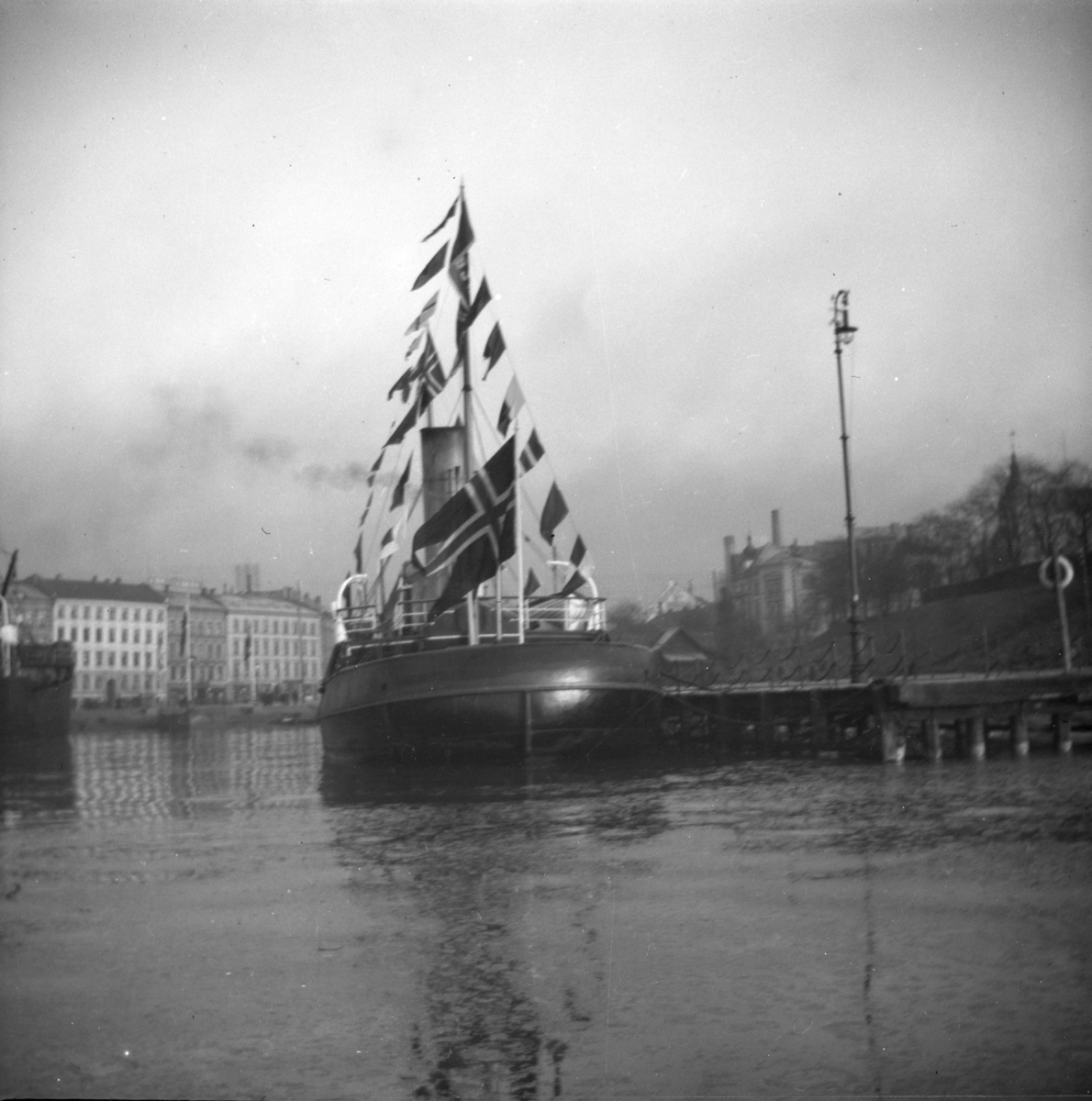 Christiania, båt pyntet med vimpler ved Akershus kai med Piperviken bak i bilde