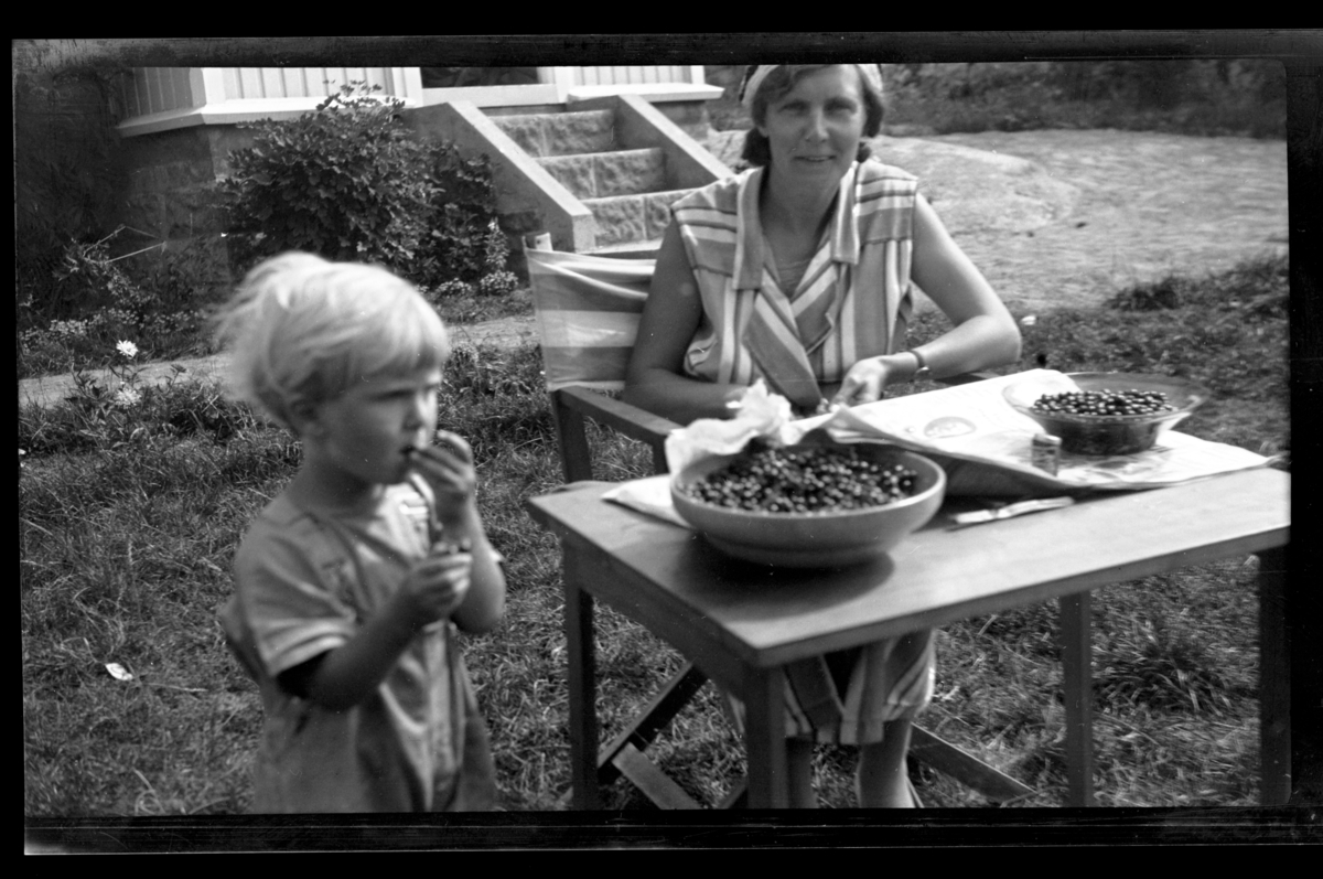 Hilda Sundt og sønnen Lars Peter renser bær, antagelig solbær, ute i hage på i Vestfold. Fotografert 1932.