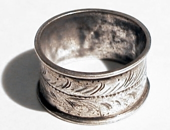 Fingering av silver med upphöjda kanter. Dekorerad med en graverad slinga samt en pärlrand som går längs hela ringen.