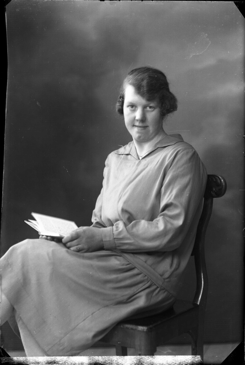 Karin Lindström sitter med en uppslagen bok i knät, 1929