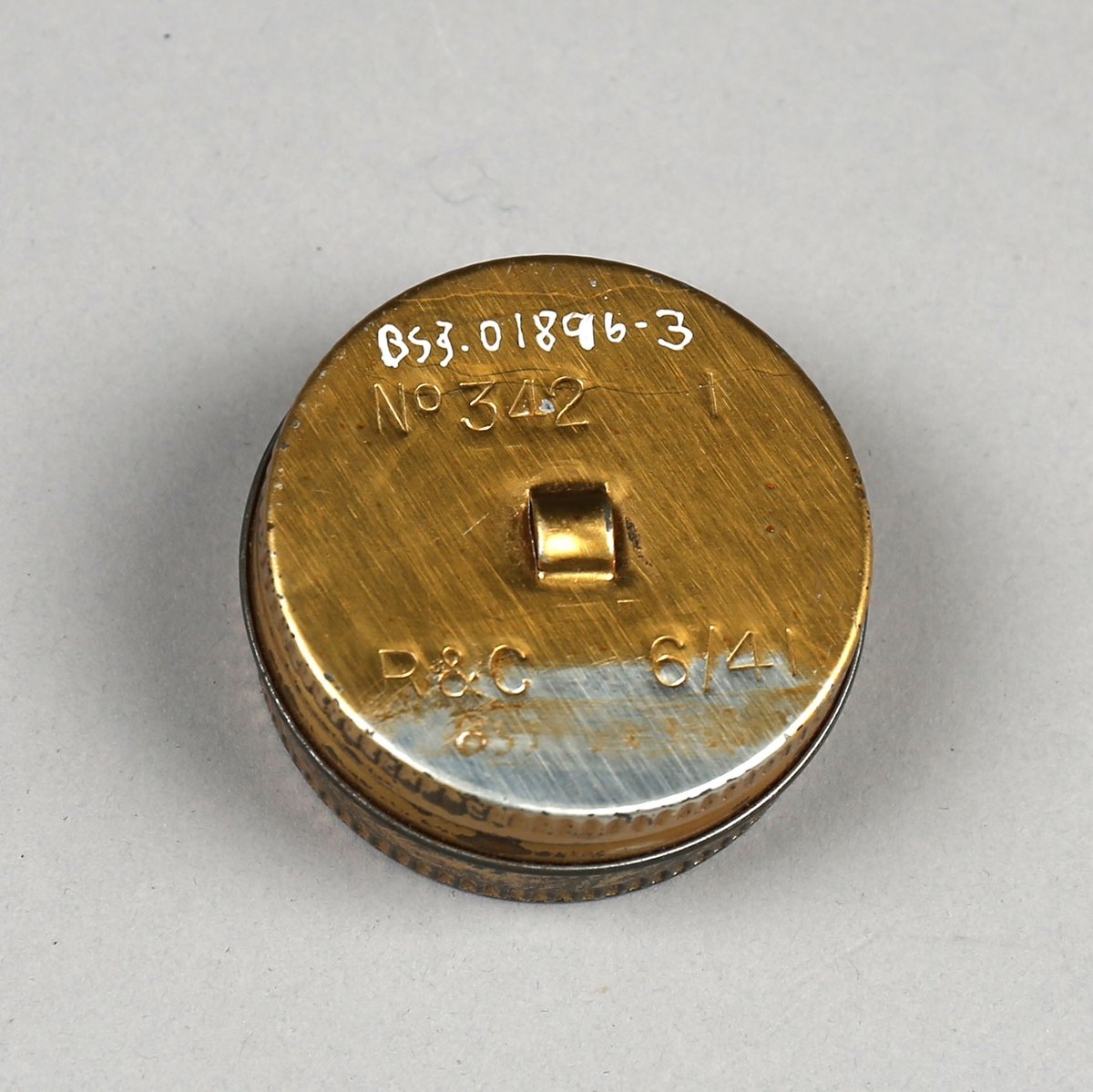 Liten rund beholder i metall med lokk. Inneholder en liten pusseklut. Oppbevares i lomme i tøyveske til gassmaske.