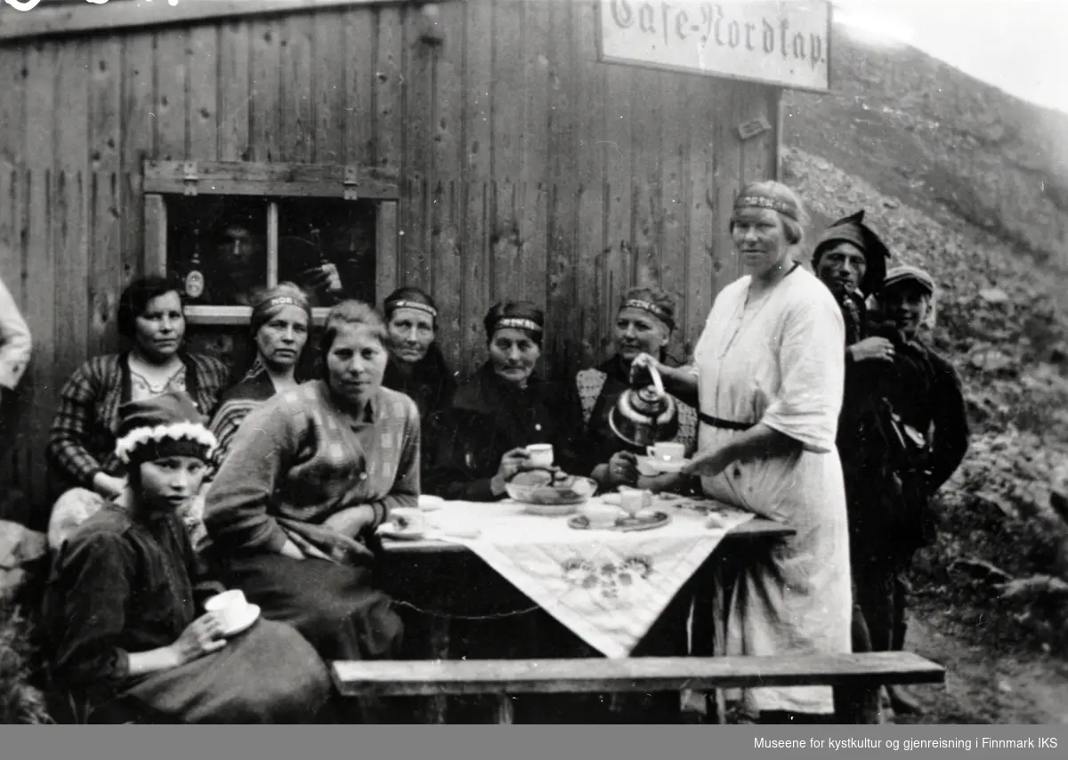 Utenfor 'Café Nordkap', antakelig Severine kafé ovenfor Hornvika. Severine skjenker kaffe til lokal kvinner og menn. 1930-tallet.