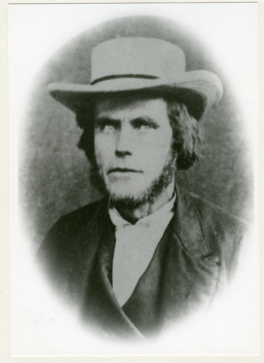 Portrett i halvfigur av ung mann med skjegg og hatt.