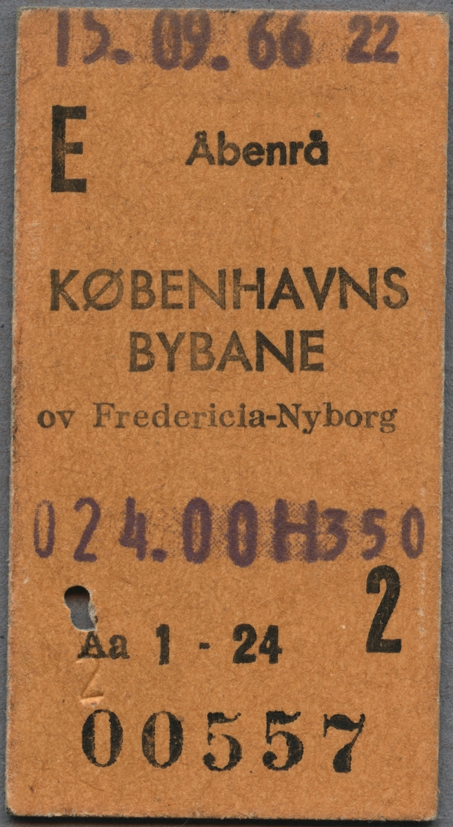 Edmonsonsk biljett av brun kartong med tryckt svart text:
"E Åbenrå
KØBENHAVNS BYBANE ov Fredericia-Nyborg
024.00 2". 
Biljetten har datumet 15.09.66 stämplat högst upp samt ett hål efter biljettång. När biljettången användes blev också "2" präglat på framsidan intill hålet. Biljettnumret "00557" står i nederkant.