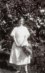 Olga Abrahamsen (1895-1986), kledd i kvit kjole og med en bu