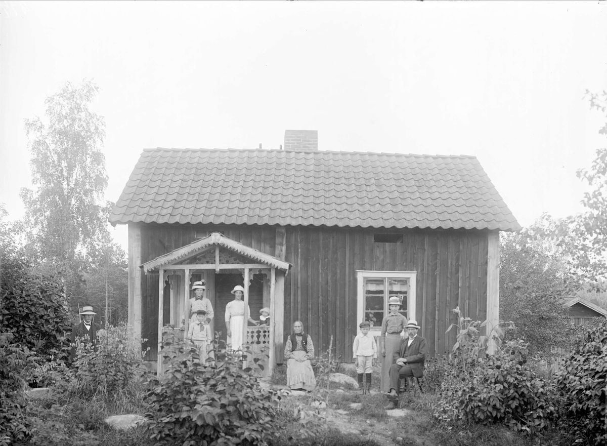 Familjen Lundin med flera framför bostadshus i Dragkärret, Tärna socken, Uppland, före ombyggnaden 1918