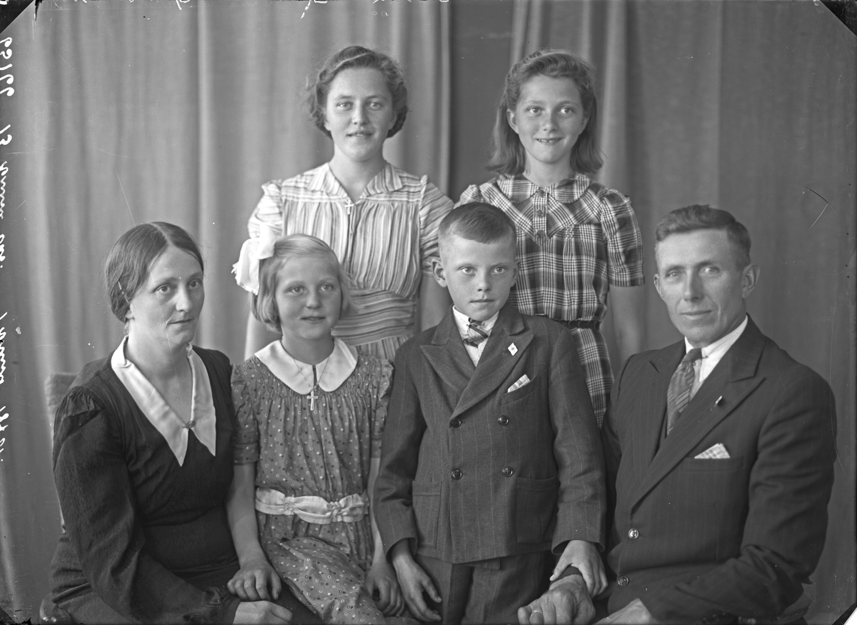 Portrett. Familiegruppe på seks. Mor, far, 3 unge piker og en ung gutt. Bestilt av John Evje. Tysværvåg.