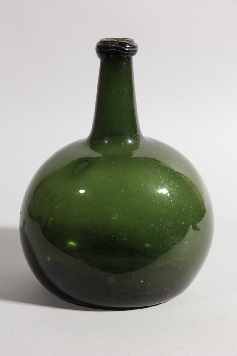 Flaska av grönt glas, rund med tillplattade sidor och hög hals.