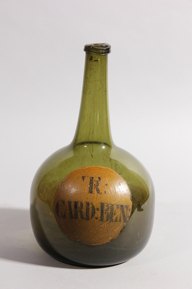 Flaska av grönt glas, rund med flat botten och hög hals.