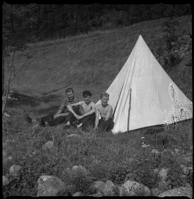 Styrhuset til lastebåten "Zita" i fart, med grus eller sand ombord. Det er også bilder av familien Skjold og tre gutter foran et telt. På bilde nr. 5 er Frida Johannessen nr. 2 fra venstre.