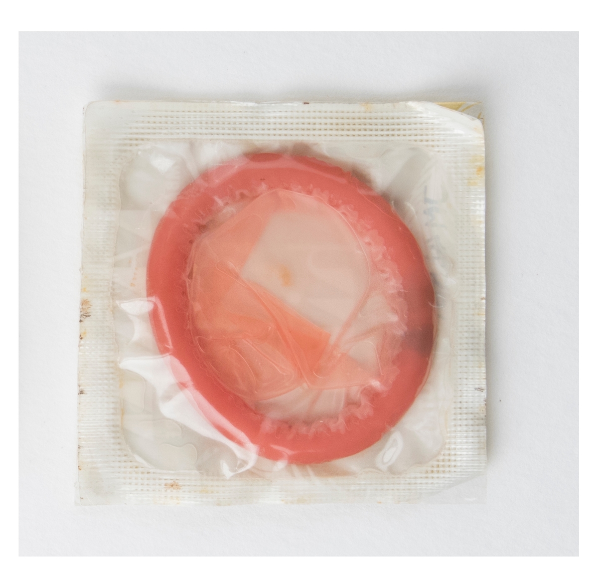 Rosa ihoprullad kondom i förpackning.