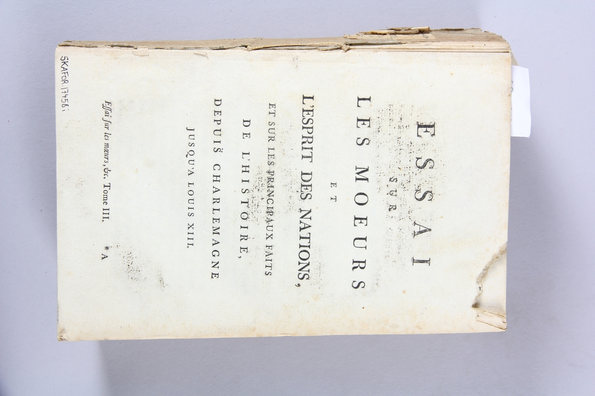 Bok, häftad,"Oeuvres complètes de Voltaire", del 18, tryckt 1785.
Pärm av gråblått papper, på pärmens baksida klistrad sida ur annan bok. Med skurna snitt. På ryggen klistrad pappersetikett med tryckt text samt volymens nummer. Ryggen blekt.