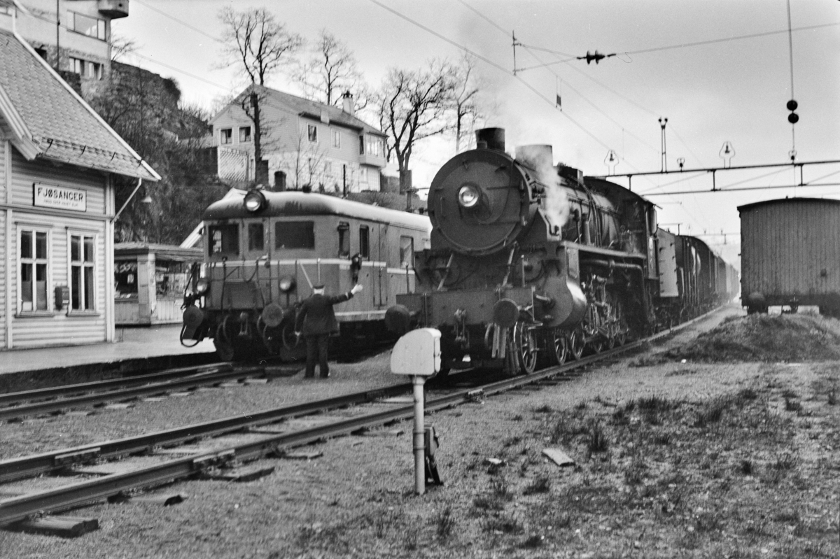 Kryssing på Fjøsanger stasjon mellomllokaltog reting Voss, tog 624, og godstog til Bergen, tog 5515. Godstoget trekkes av damplokomotiv type 31b nr 426. Fremst i lokaltoget styrevogn type BFo4b.