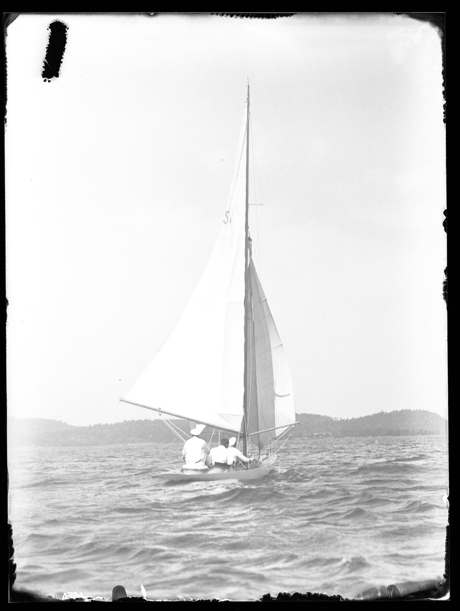 Alingsås Segelssällskaps utlåtningsbåt fotograferad ute till sjöss med tre personer ombord.