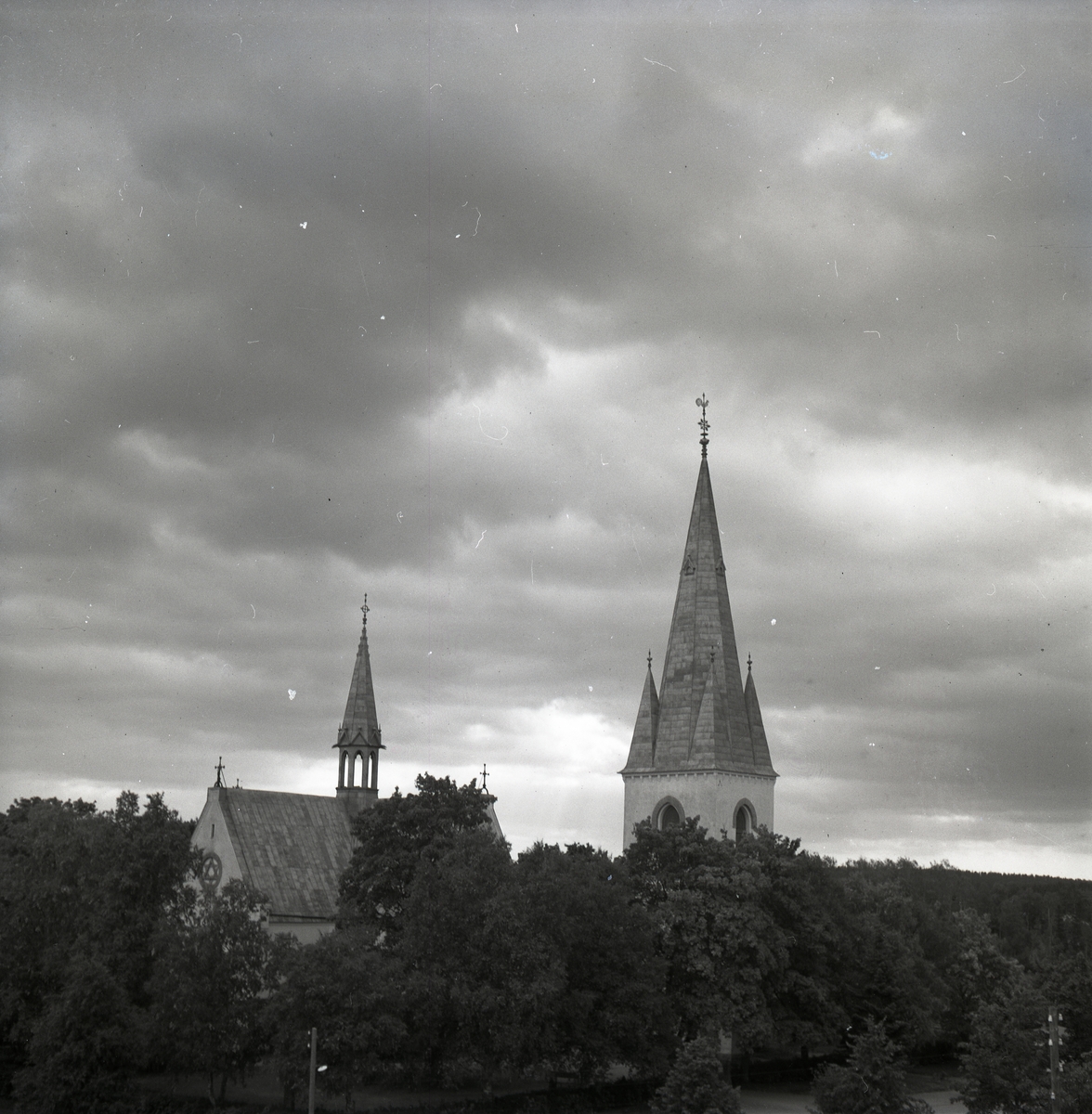 Bland trädtopparna sticker kyrktornet och takryttaren från Harmångers kyrka upp.