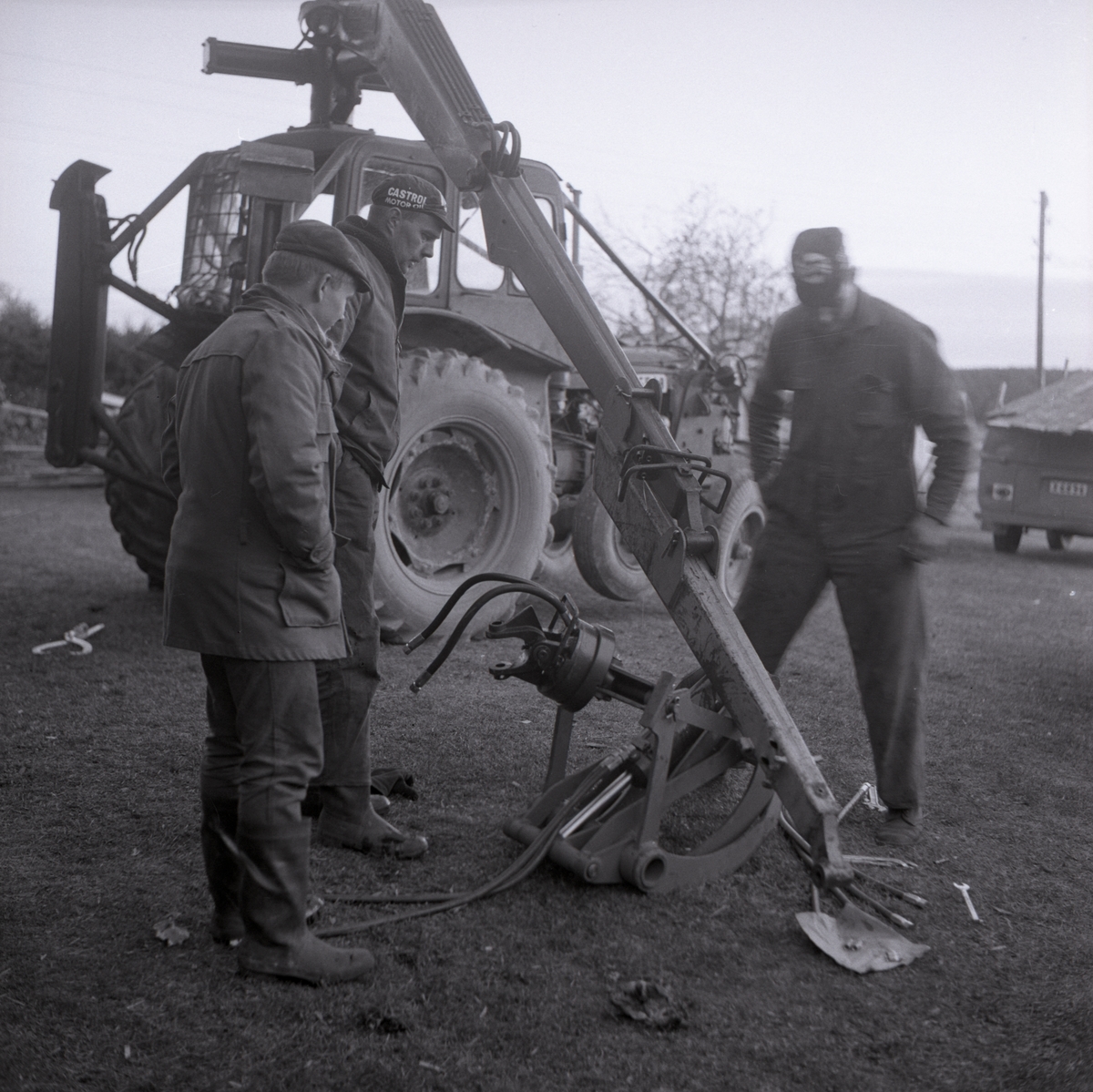 Tre män inspekterar en gripklo till en traktorn i Rengsjö, 1967.