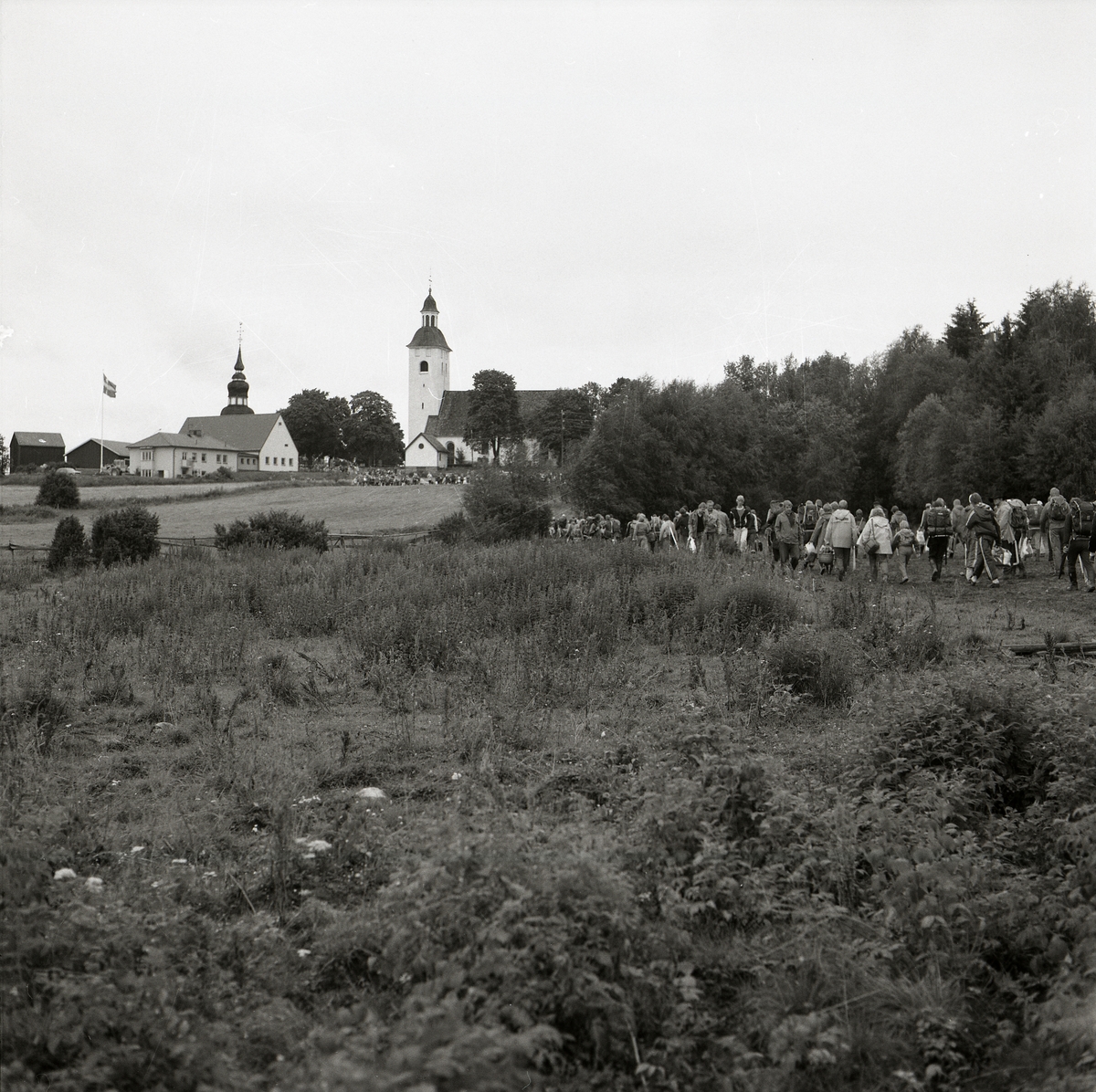 En lång rad människor tågar mot kyrkan efter orienteringstävlingar i Hälsingtuna den 20-24 juli 1982.