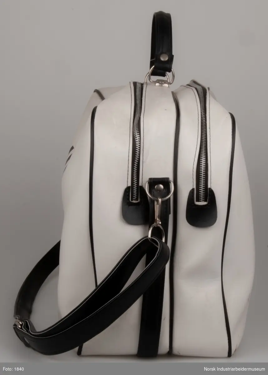 Hvid sportstaske med sort Norsk Hydro logo og sorte dekorationer. Sort skulderrem. Forsynet med to lynlåse af metal. 20x40x60 cm.