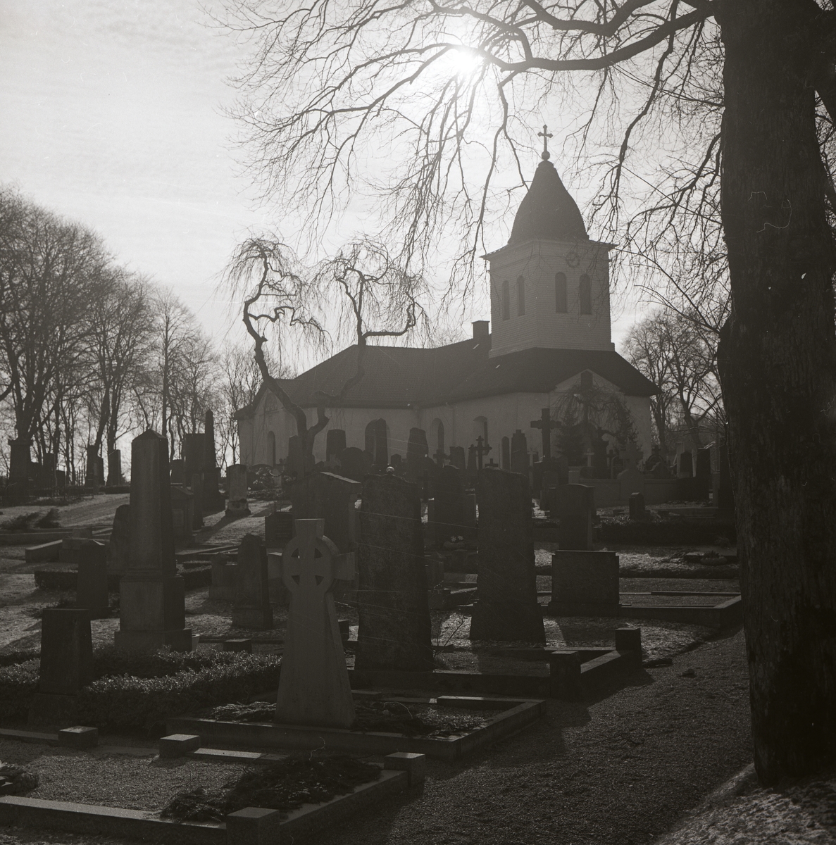 En kyrkogård med många gravstenar framför en kyrka.