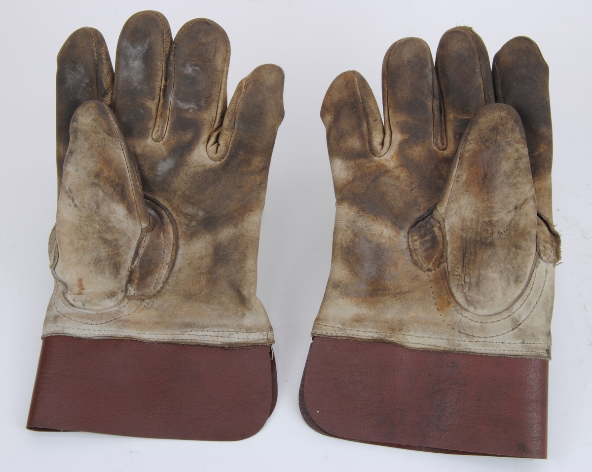 Ett par växlarhandskar av typen fingerhandske. Tillverkade av ljust skinn. Handskens krage av brunt skinn.