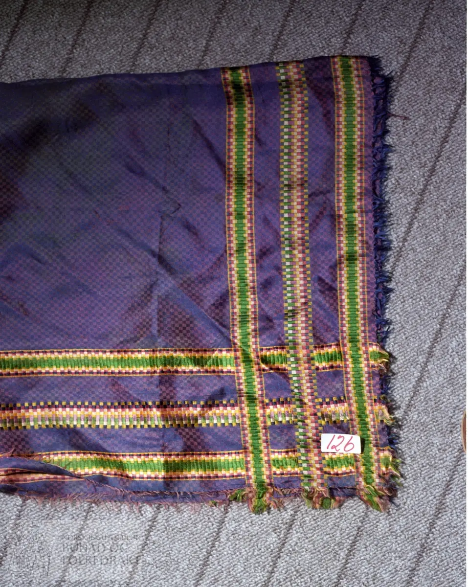 Tørkle i dreielsruter, lilla med kjerringtannbordar i fleire fargar.  83 x 84 cm.