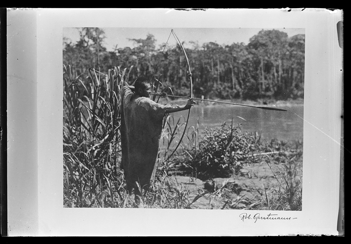 En man står vid kanten av ett vattendrag och spänner en pilbåge. Bilden är signerad Rob. Gerstmann. I Harald Olssons anteckningar står det "27 rep. för Folke Olsson".