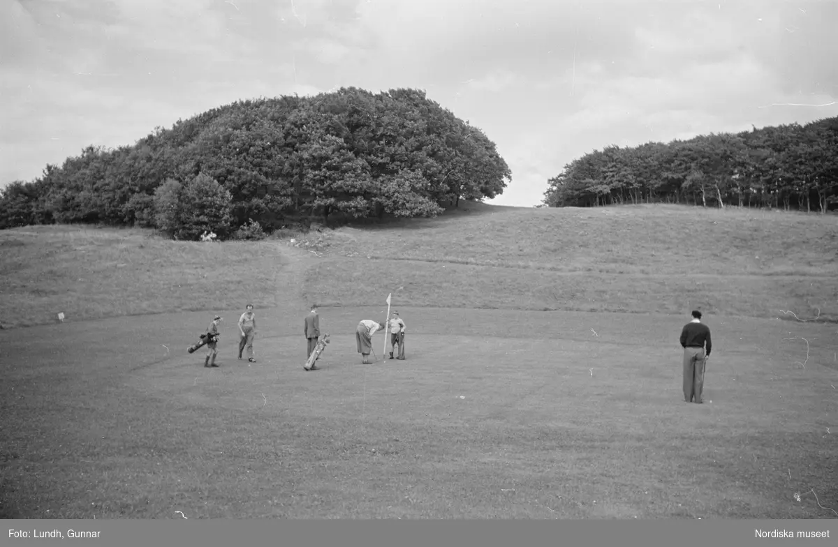 Mölle Golfklubb. Dåvarande kronprinsen Gustaf Adolf (nr 4 fr v), med prins Bertil (troligen) längst t h, på klubbens golfbana i samband med invigningen 6 juli 1945.