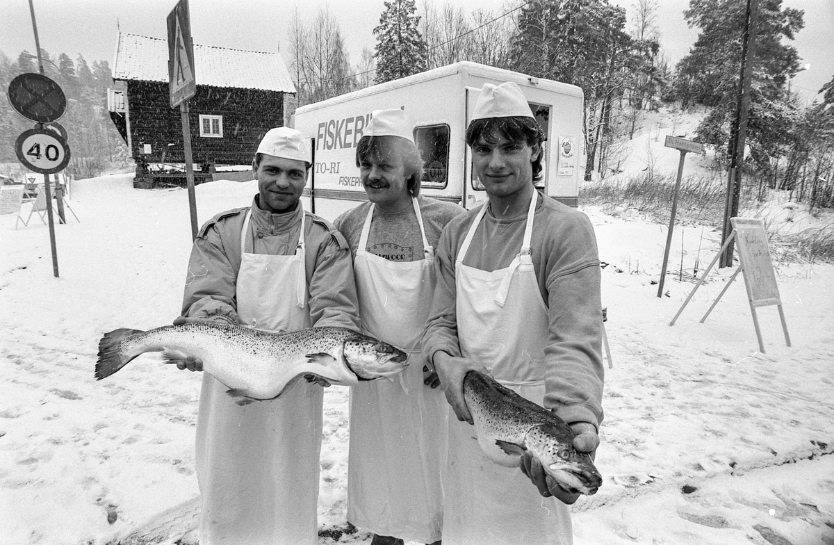 Fiskebilen i Oppegård. Tre menn står utenfor fiskebilen med laks eller ørret. Selger Atle Memo og innehaverne Tom Hille og Rino Memo.