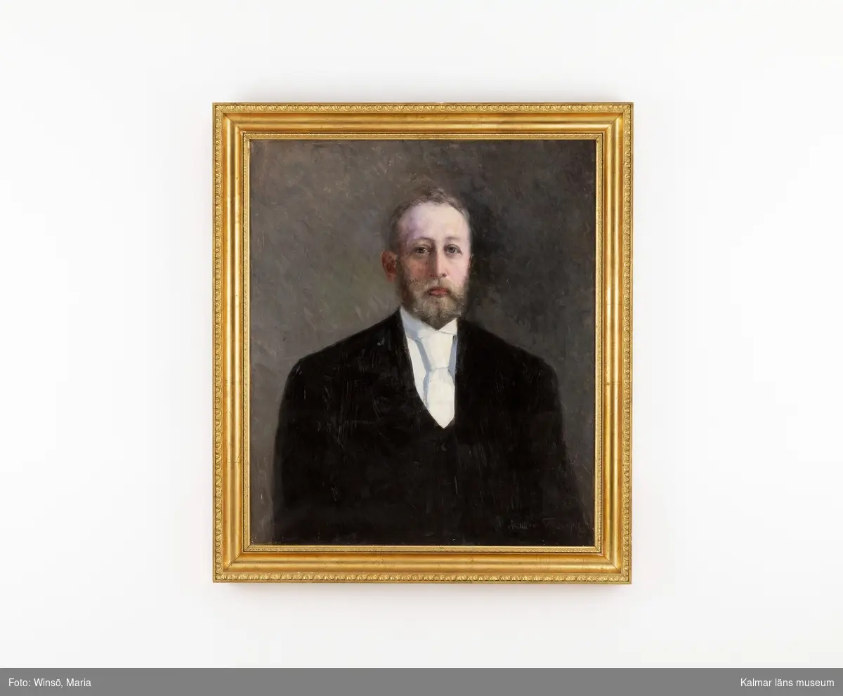 Porträtt av Bror Hain, midjebild. Man med skägg. Klädd i svart rock och väst, vit skjorta och slips.