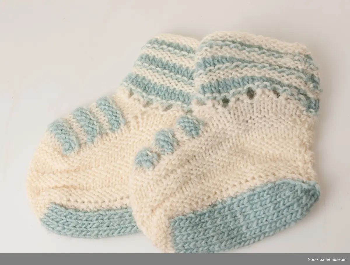 Hvite strikkede sokker med lyseblå detaljer.