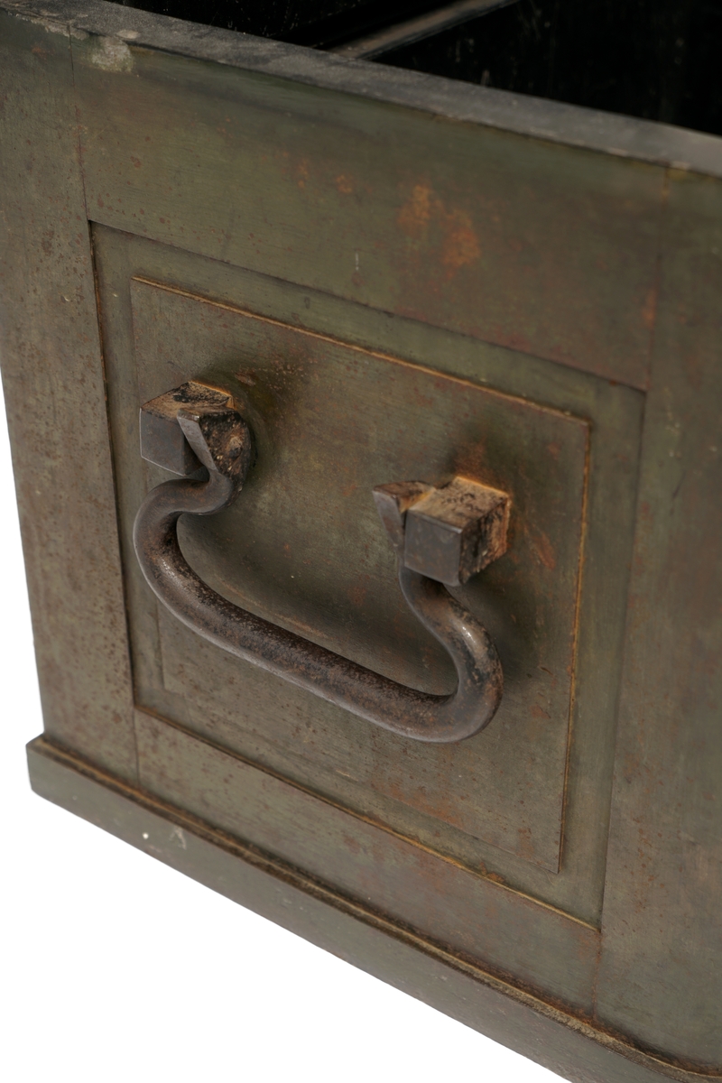 Jernkiste med lokk og med nøkkelhull i lokket. Kraftige låsebøyler og beslag av jern.  Kraftige jernhåndtak er montert på begge sider. Kisten er dekorert med innstøpte blomsterlignende ornamenter