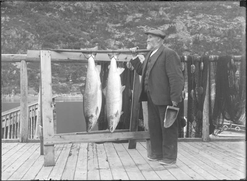 Kjøpmann C. W. Johansen på bryggen sin med to lakser.