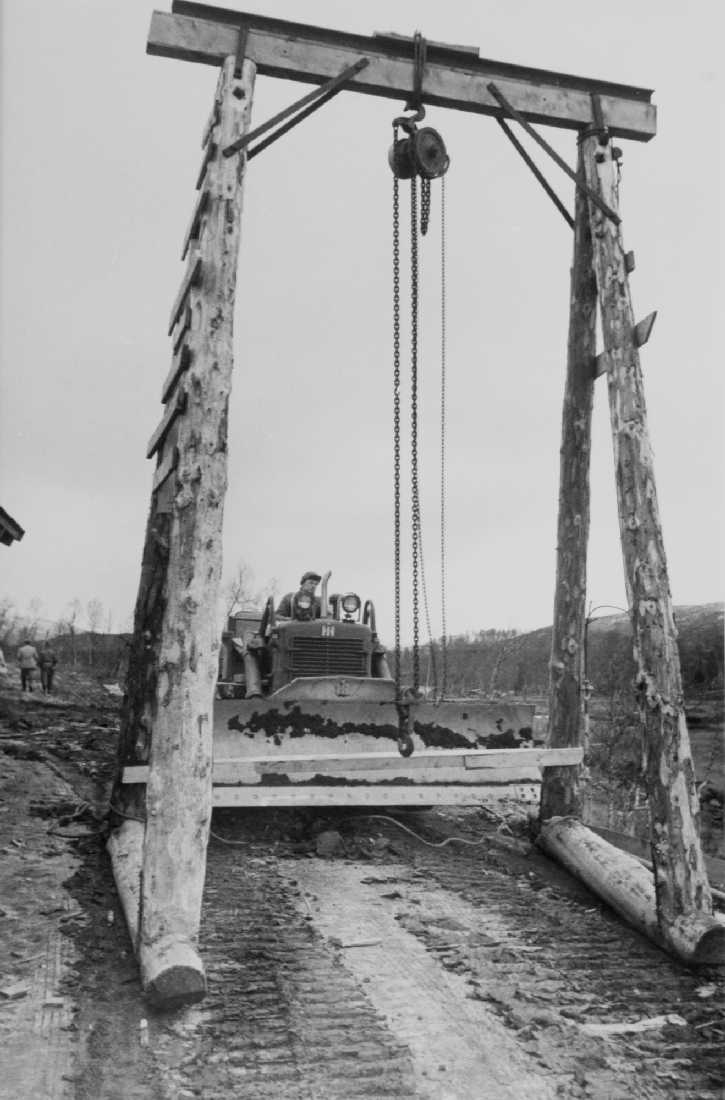Nedre Røssåga, opprinnelig arkivnr. 0286-a.
Tustervatnet. Tverrslag tilløpstunnelen, etablering av tverrslag. Bulldoser (International Harvester) som flytter en løftebukk av tømmer med kjettingtalje.