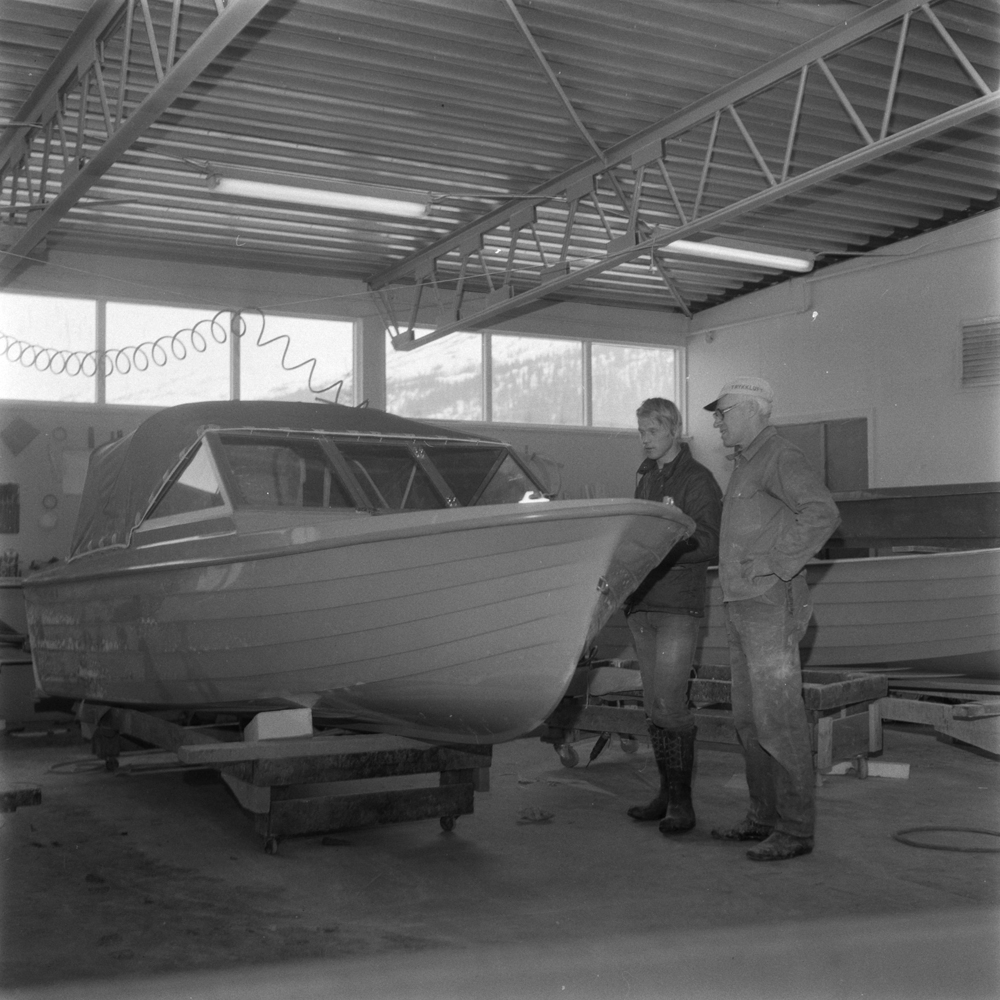 Båtfabrikken Polar-Industri A/S i Drevvatnet. Inne på fabrikken. 2 menn ved siden av båt som er/begynner å bli ferdig.Driftsleder Einar Drevvatne og Jarle Dalheim
