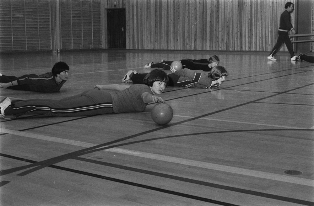 Trimtreff i Mosjøen. I gymsalen på Kippermoen eller Gymnaset. Kvinner og menn som gjør gymnastikk med ball ledet av instruktør.
