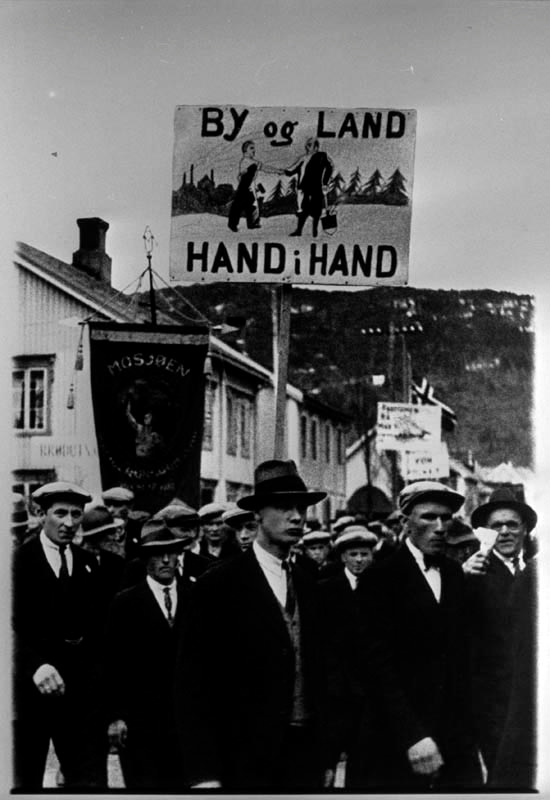 1.mai toget i Mosjøen. Demonstrasjonstog. Plakater. "By og land hand i hand". Usikkert årstall.