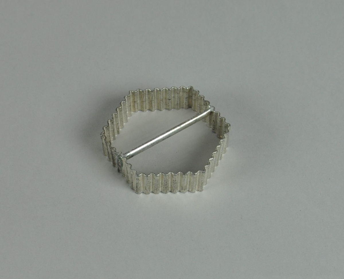 Kakeform av aluminium. Sekskantet form med bølgete profil og hank på midten.