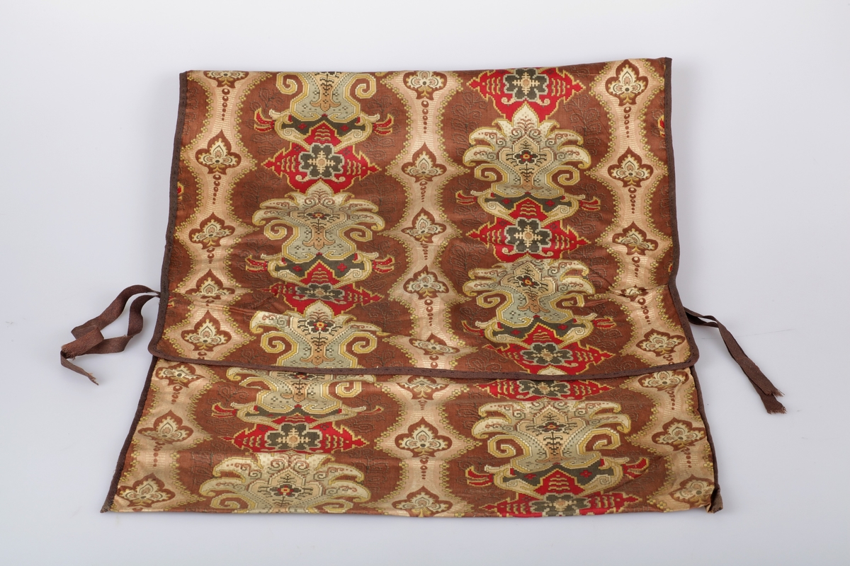 Tøypose i trykt, mønstret bomullsstoff. Sydd for hånd, og kantet med brunt bånd.