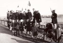 17. mai-tog i Vadsø 1945 med barn som sitter på gjerdet. Vad