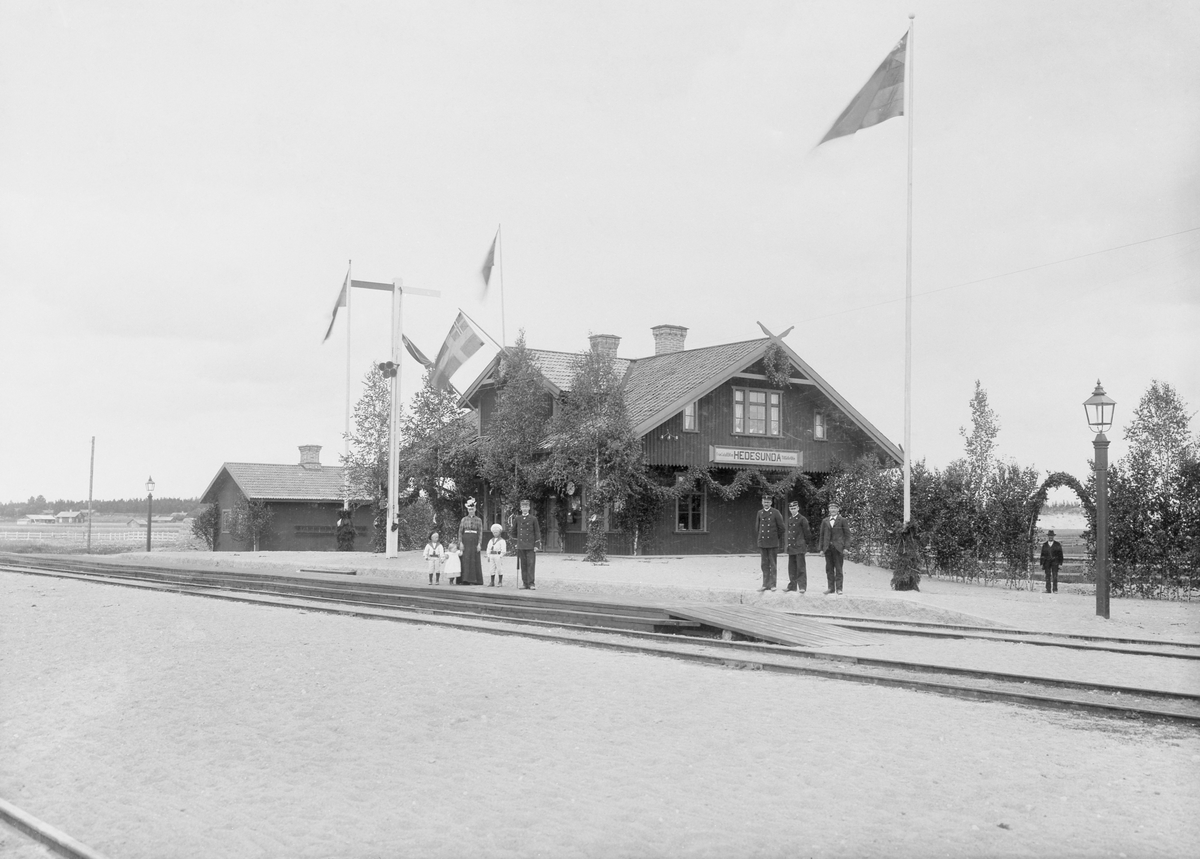 Hedesunda station utsmyckad i samband med banans invigning 29 juni 1901. Längst fram på perrongen, till höger, står den förste stationsinspektorn vid Hedesunda, Axel Bylander född 1866. Till vänster om honom syns hans familj. Till höger i bild är i riktning mot Sala.