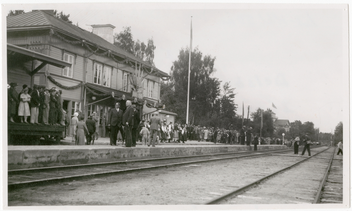 Ljusdal-Hudiksvall 50 år
Delsbo station 1938 i väntan på jubileumståget 1888-1938.
28 Augusti 1938.
Station anlagd 1888. Tvåvånings stationshus i trä. 1938 utökades stationen med poststation och godsmagasin samt moderniserades expeditionen