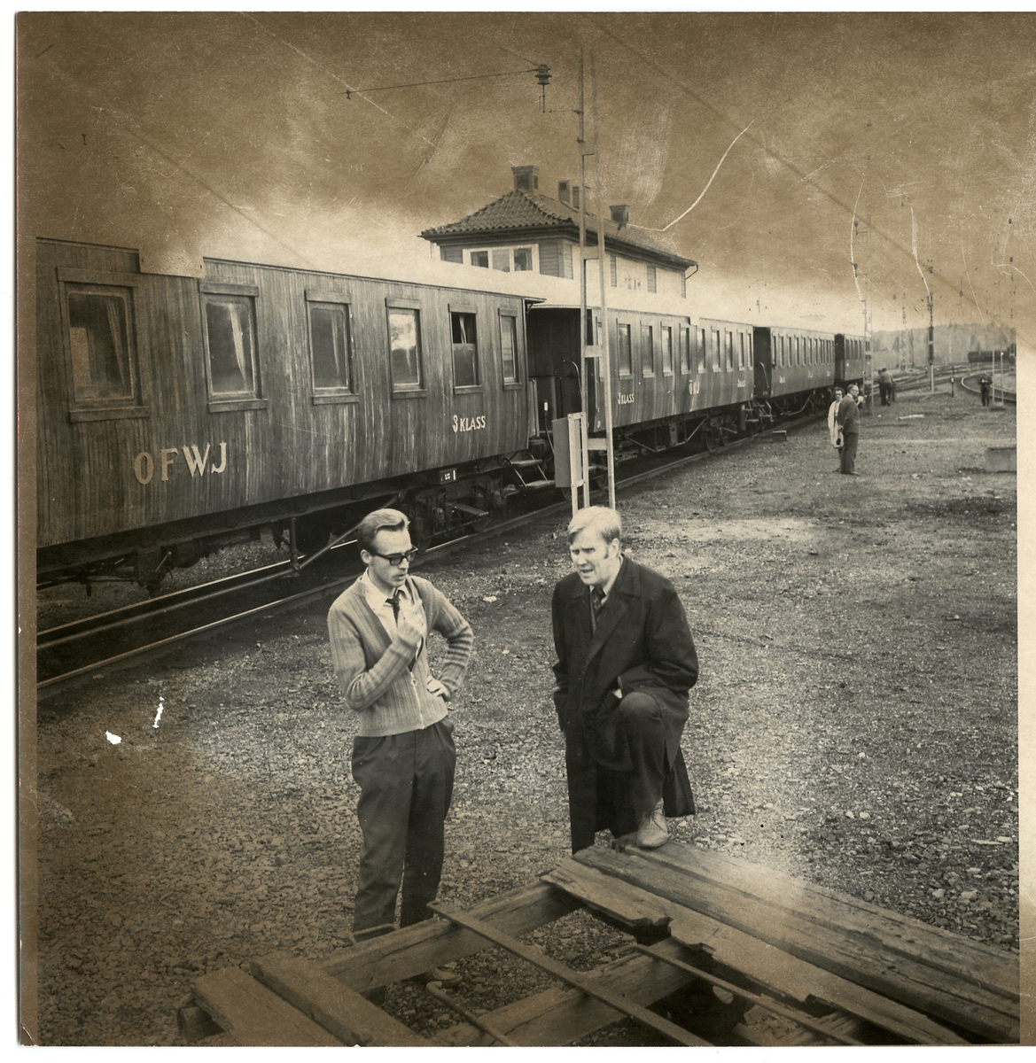 Samling av äldre järnvägsvagnar. Entusiasten Fredriksson och lokinspektor H. Halvarsson i samspråk medan tåget gör uppehåll på Grängesberg malmbangård.