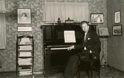 Gottfred Pedersen sittende ved pianoet i stua i Amtmannsgt. 