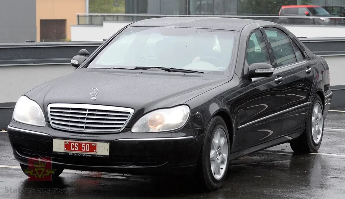 Mercedes-Benz S 600L. 4-dørs karosseri, svart lakk. Hvitt interiør. Bilen har en vannavkjølt, bensindrevet 12-sylindret V-motor (V 12) med turbo. Motoren har et sylindervolum på 5513 kubikkcentimeter. Motorytelse/effekt 500 hk/368 kW. Antall sitteplasser er 4. Dekk foran og bak skal standard være 235-700R450AC P.