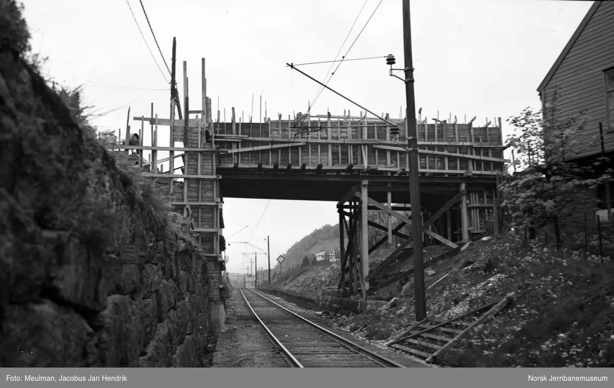 Arbeid med heving av overgangsbro i forbindelse med elektrifiseringen av Vossebanen. Forskaling av liggerne. Her ved Jansen fabrikker ved Midttun, sett i retning fra Bergen.