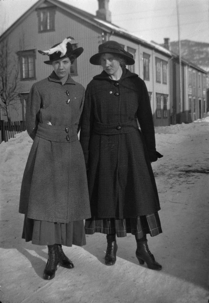 To kvinner med fjonge hatter og kåper. Snø i gaten.
