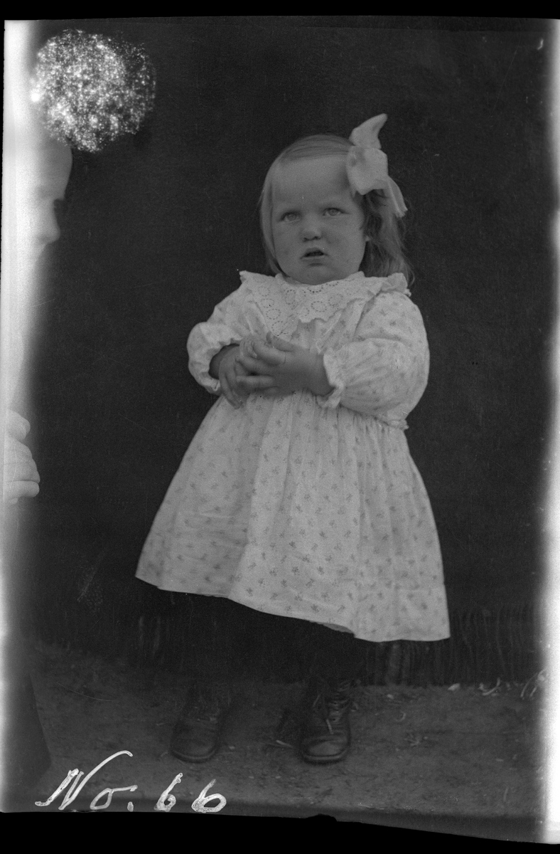 Portrett av liten pike foran et opphengt pledd.