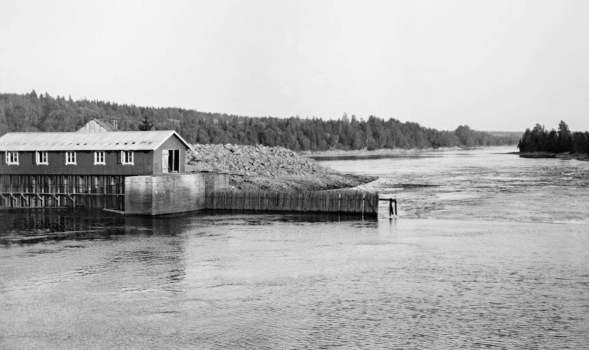 Nåledam - såkalt «fermettedam» - ved Vormas østre bredd ved Svanfossen i Fenstad i Nes kommune på Øvre Romerike, fotografert i 1916.  Den øvre delen av dette vassdraget ble noe regulert i slutten av 1850-åra, for å gjøre det mulig å kople den da nyetablerte hovedbanen med dampskipsruter på Mjøsa. Den første dammen ved Svanfossen skal ha vært bygd i 1910.  Her ser vi (til venstre i forgrunnen) hvordan elva faller over en terskel på elvebotnen. På den østre delen av denne var det montert en såkalt «fermettedam», en stålkonstruksjon som bærer ei gangbru, der fløterne kunne gå når de skulle «sette dammen» (stenge) eller «sprette» (åpne) den. Dette ble gjort ved hjelp av «nåler», plank som ble stukket mot strømmen, slik at den lå an mot en terskel i botnen av elveløpet og mot gangbrua.  Disse nålene ble satt tett i tett, slik at de sammen dannet en vegg mot vannet. Når dammen ble åpnet, brukte karene små kjetting- eller taustubber med ei jernnål i enden, som ble tredd gjennom hull i den øvre delen av nålene, og trakk til. Fermettedammen ved Svanfossen skal ha vært ferdigstilt 8. september 1916.