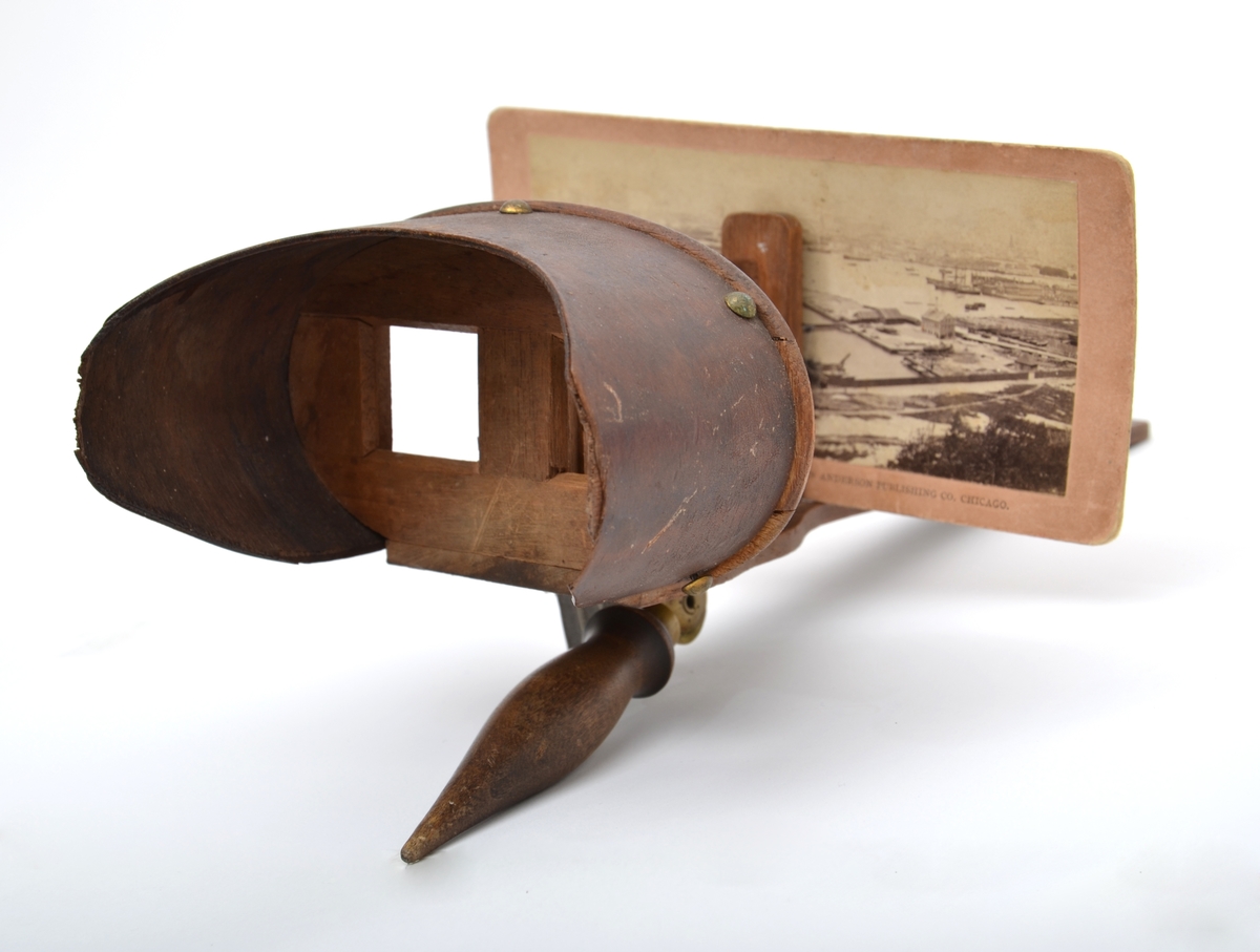 Et stereoskop tilvirket i mørkt ubehandlet treverk med et fint dreid sammenleggbart håndtak festet til brillen med et messingledd. Det ovale tittekammeret er utført i finer. Både rammen til å feste stereofotografiene og begge linsene mangler. 
24 stereofotografier eller stereokort fra ulike produsenter antagelig produsert på slutten av 1800-tallet hører til stereoskopet.